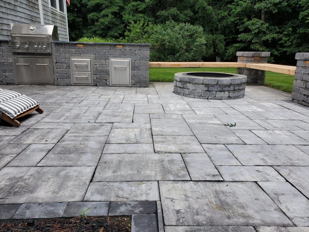 Finished Duxbury patio with outdoor kitchen and circular fire-pit area