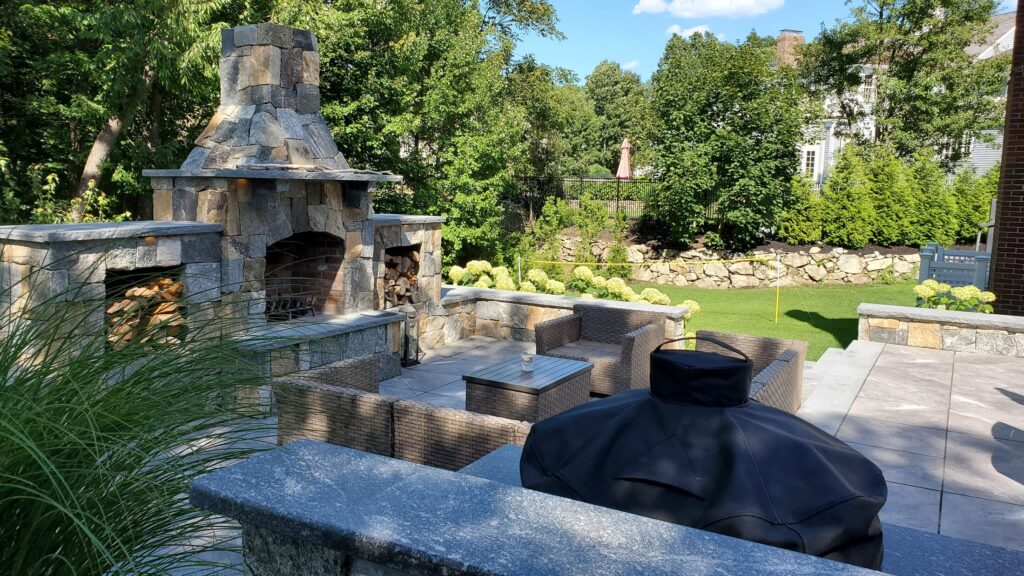 Hingham masonry fireplace viewed across the outdoor kitchen