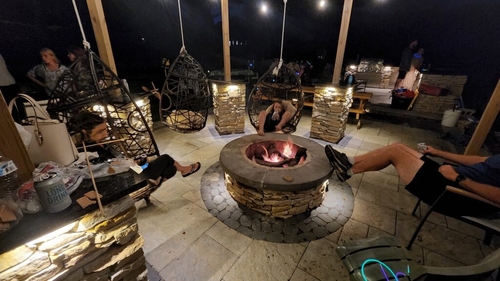 Nighttime fire feature, patio and hanging chairs at the waterfront project
